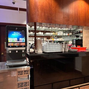 A coffee machine with a digital display and a coffee station with various items.