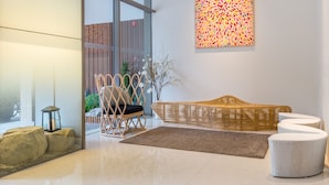 A modern interior with a large window, a wicker sofa, a small table, and a decorative wall piece. - Summer View Hotel (Singapore)