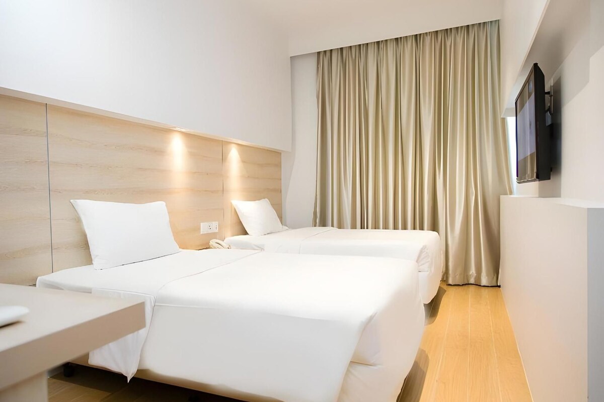 A hotel room with a bed, bedside table, and a TV mounted on the wall.