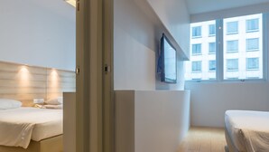 A modern hotel room with a large bed, a smaller bed, a TV mounted on the wall, and a window with a view of buildings. - Summer View Hotel (Singapore)