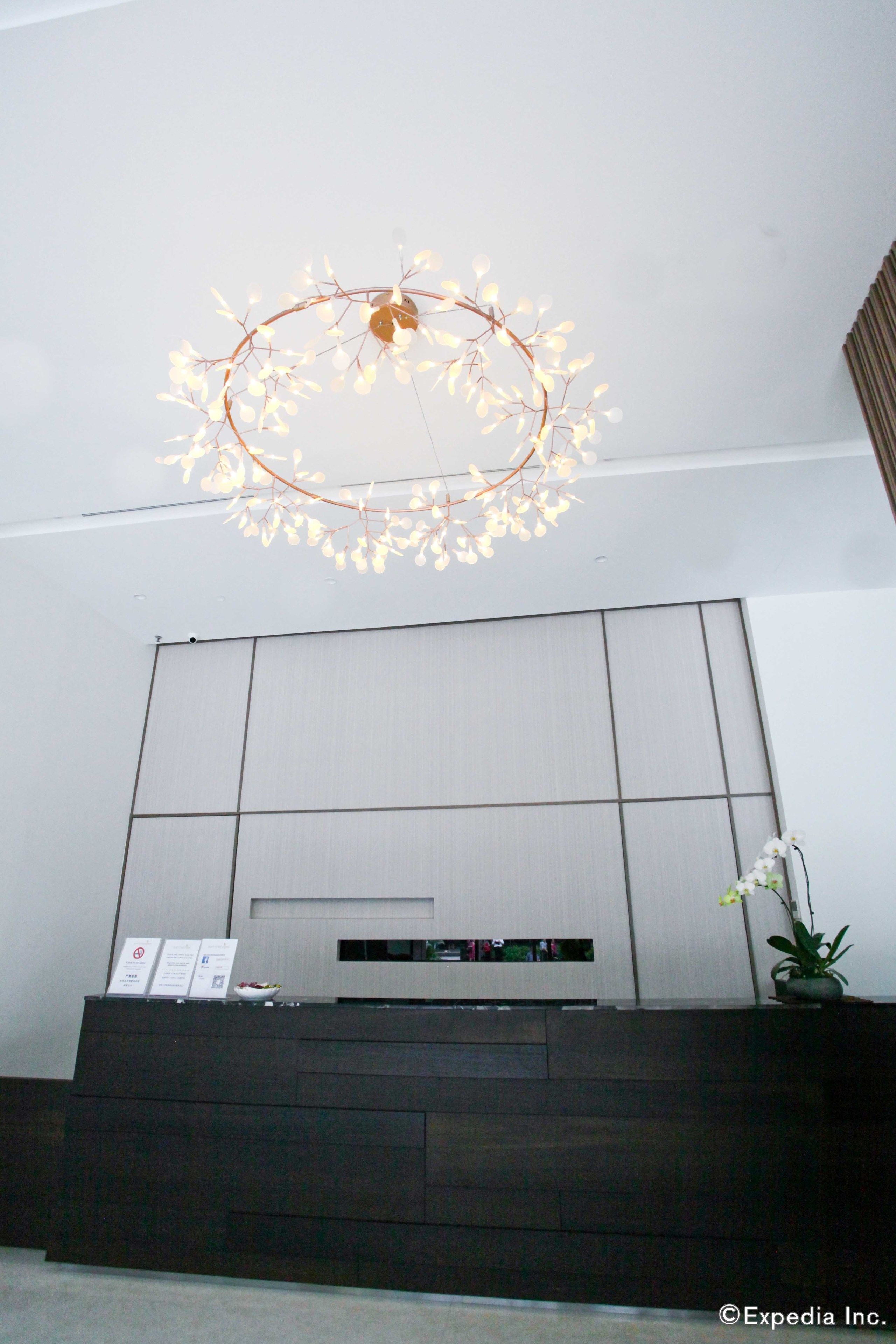 Un intérieur moderne avec un téléviseur fixé au mur, une console en bois foncé et un luminaire décoratif.
