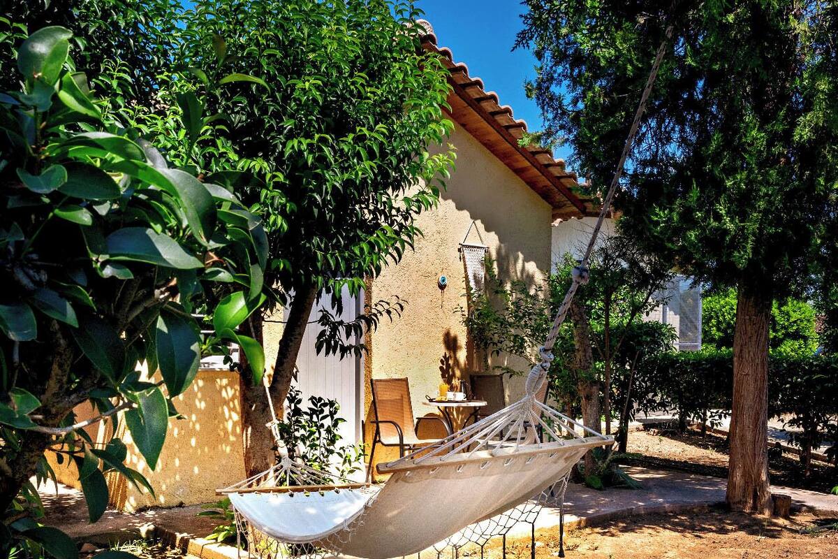 A hammock chair in a garden area with a building in the background.