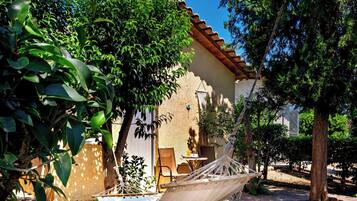 A hammock chair in a garden area with a building in the background.