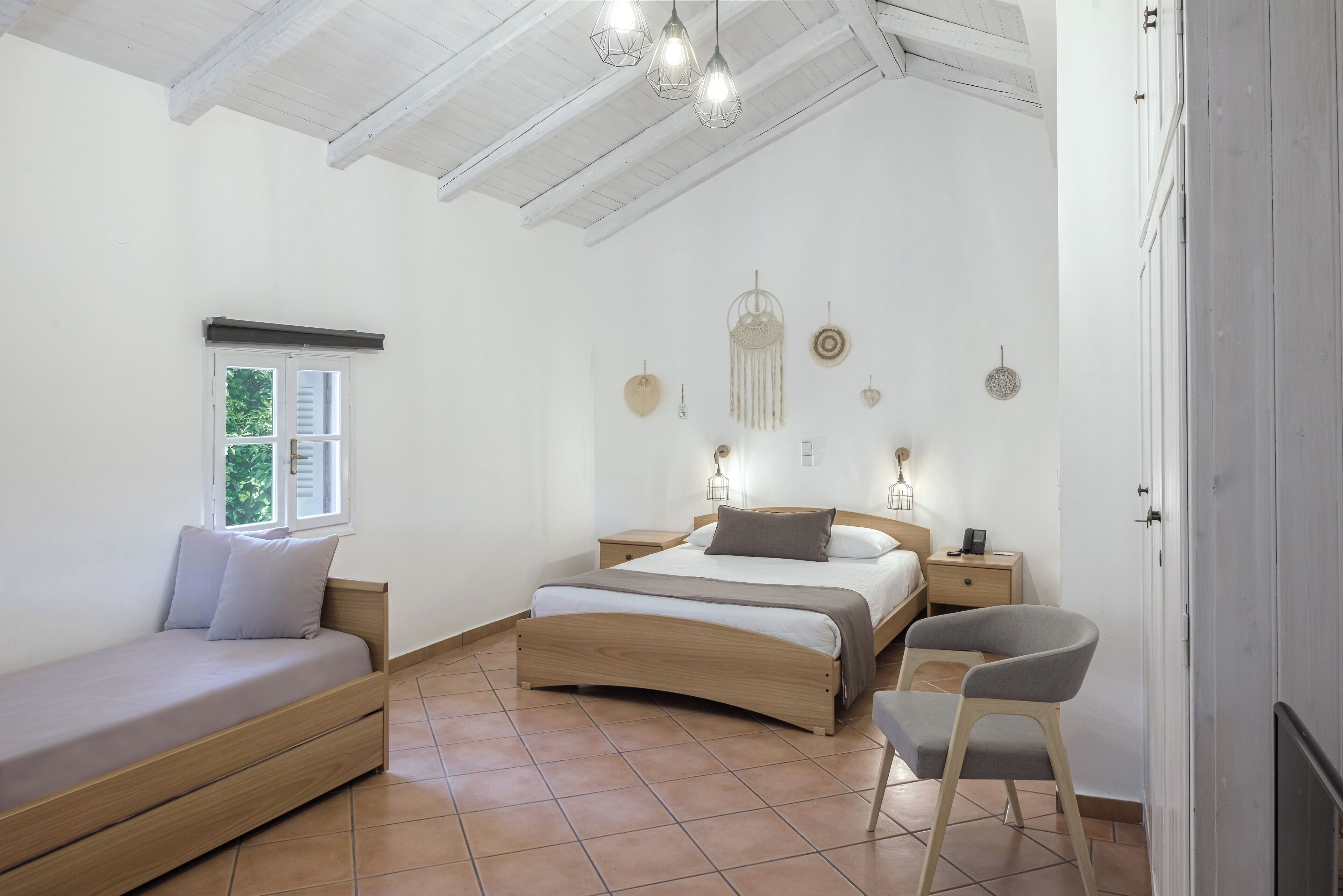 Een slaapkamer met een houten bed, een dagbed, een stoel en een raam met luiken.