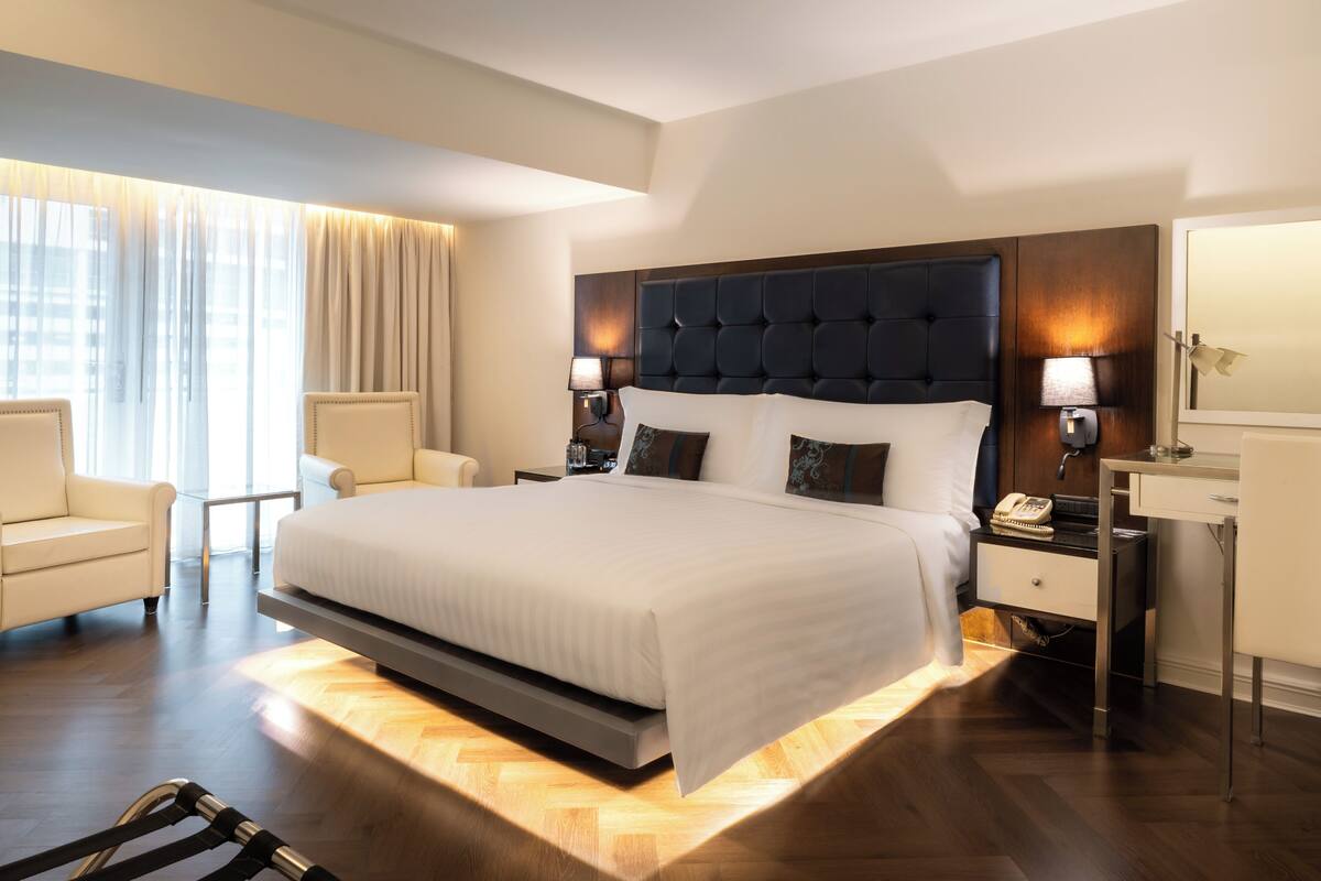 A modern hotel room with a large bed, bedside tables, a desk, and a chair.