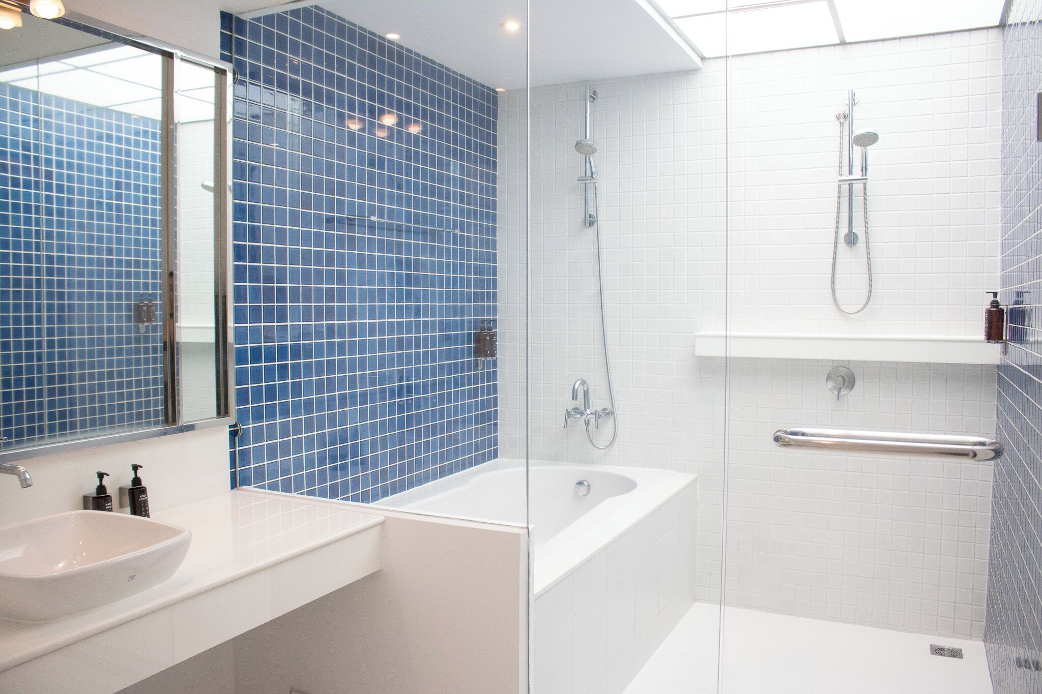 A modern bathroom with a glass-enclosed shower, a white sink, and blue-tiled walls.