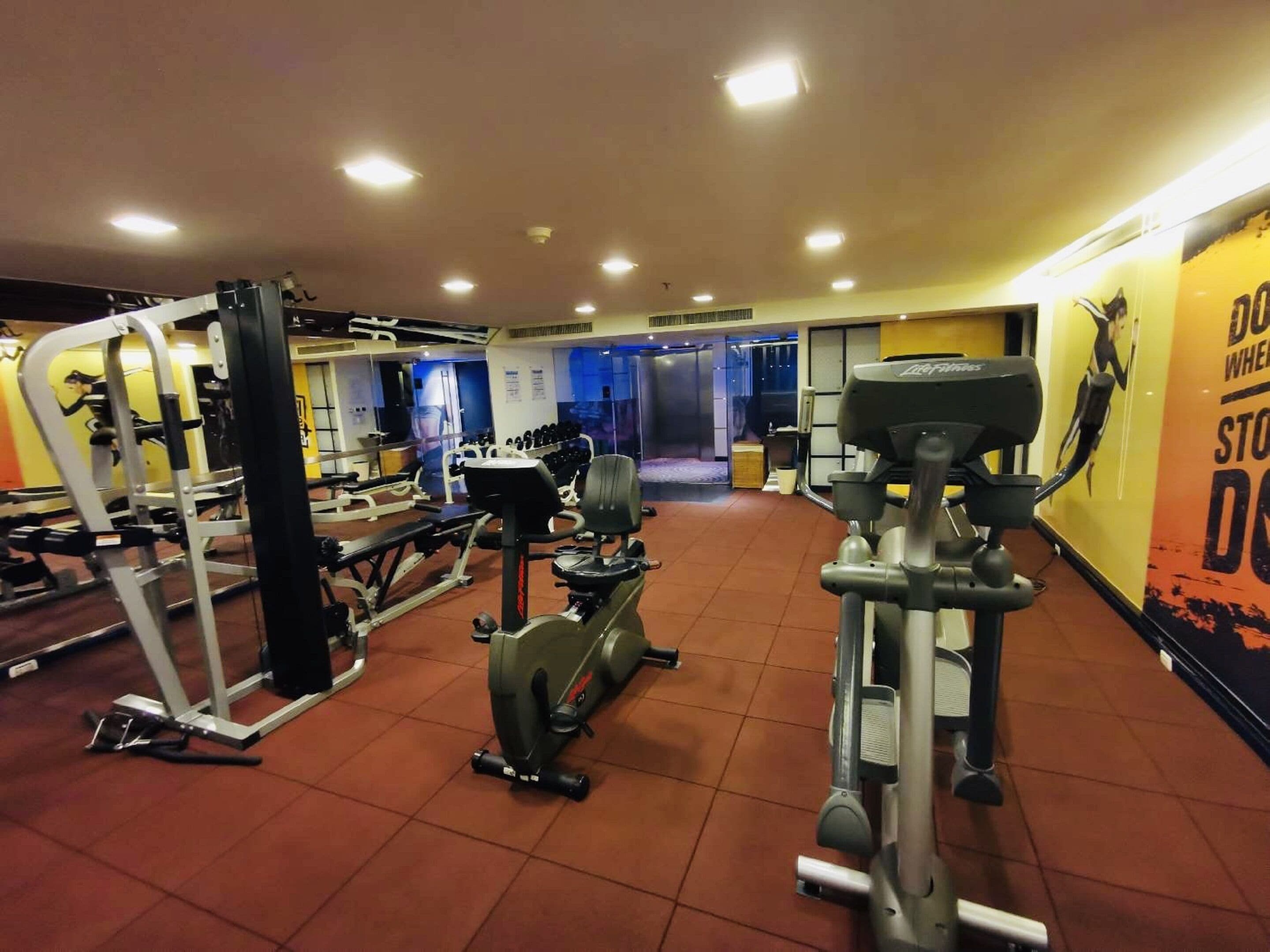 Uma academia com diversos equipamentos de exercício, incluindo esteira, elíptico e aparelhos de musculação.