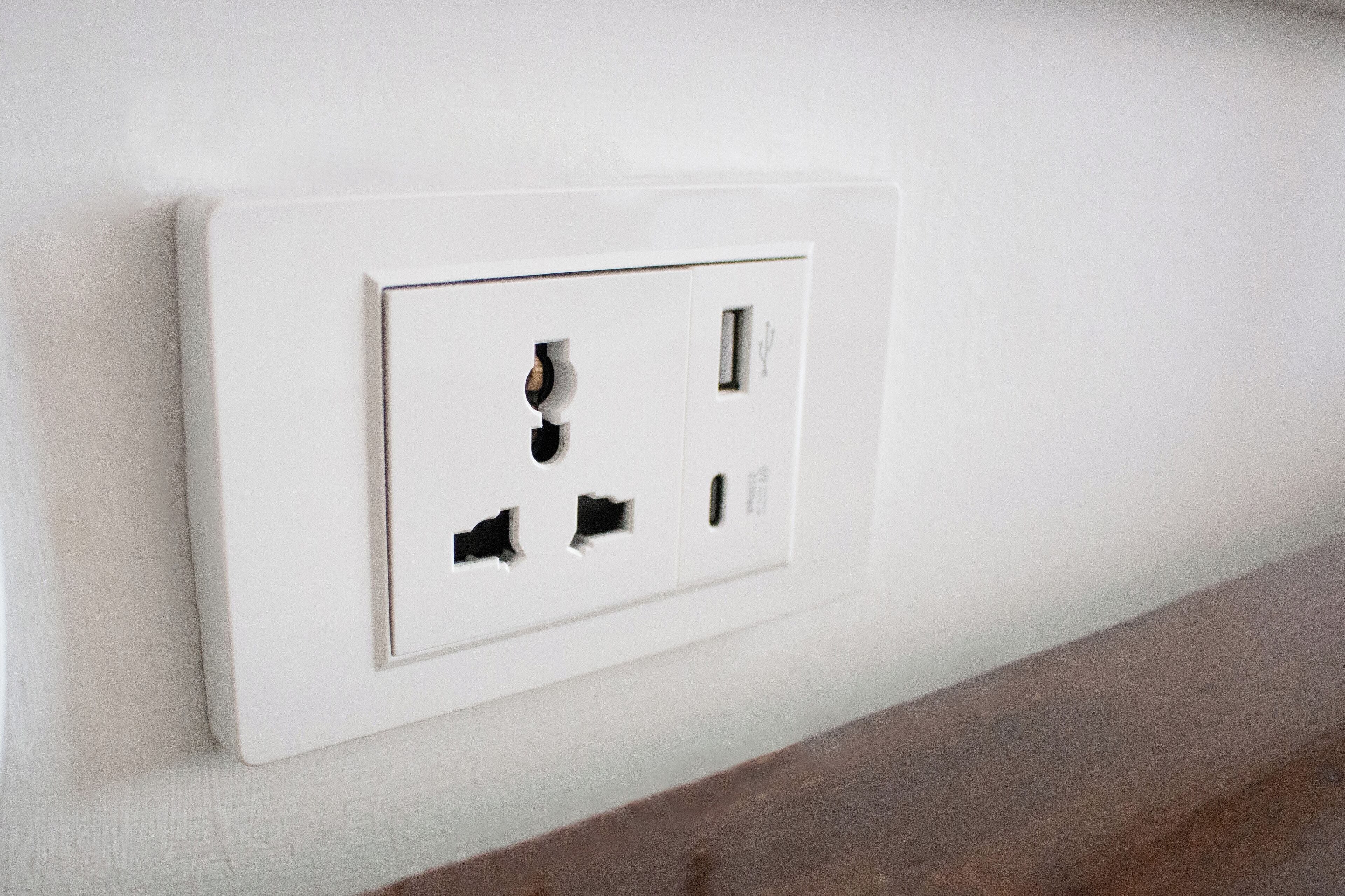 Un enchufe blanco con cuatro orificios, incluyendo un puerto USB, en una pared.