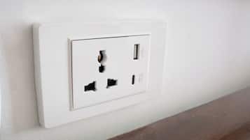 A white electrical outlet with four holes, including a USB port, on a wall.