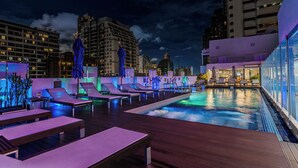Una piscina al aire libre, sombrillas, sillones reclinables de piscina