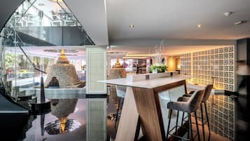 A modern interior with a glass staircase, a wooden bar area, and a patterned wall.