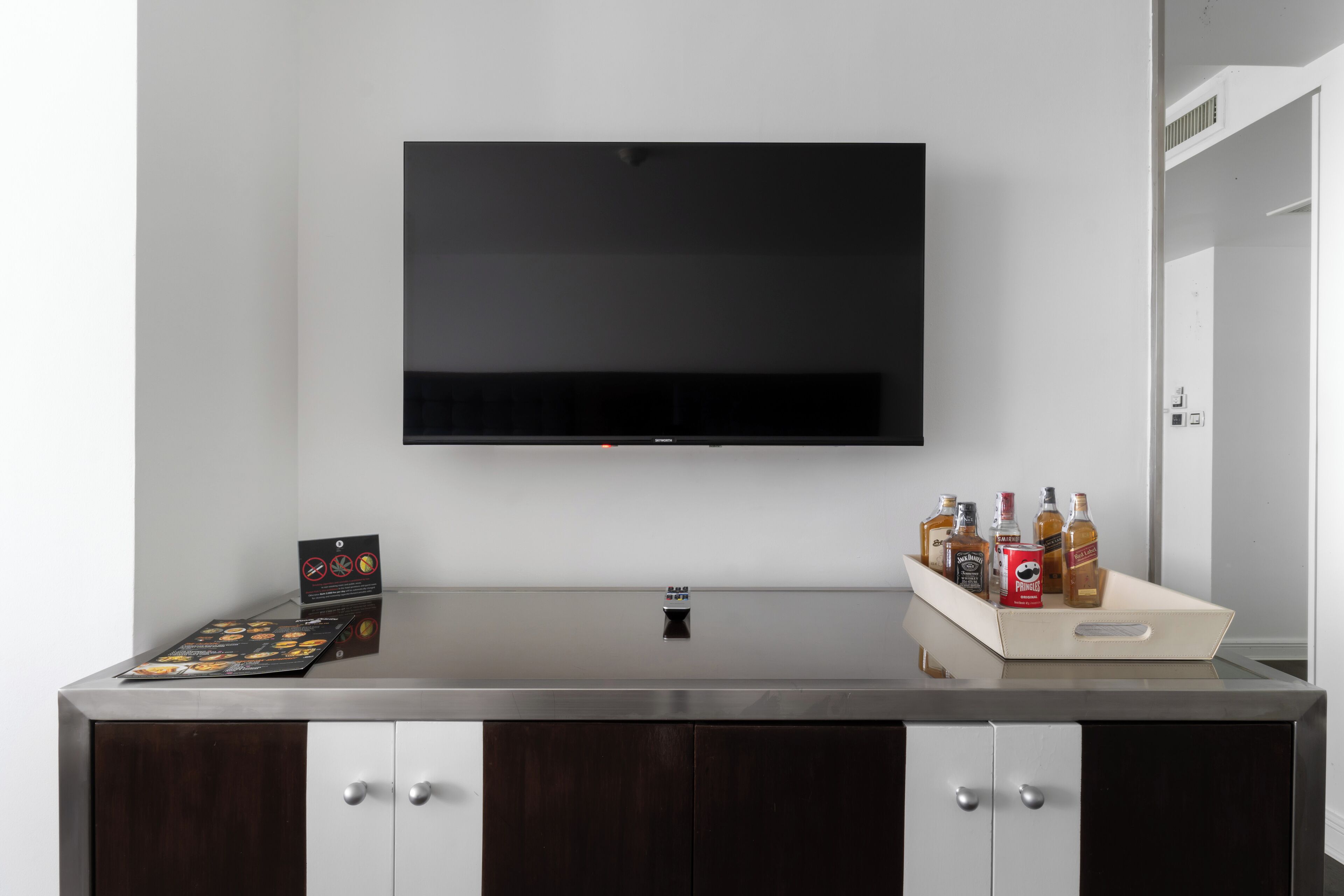 A modern kitchen with a flat-screen TV mounted above a stainless steel countertop.
