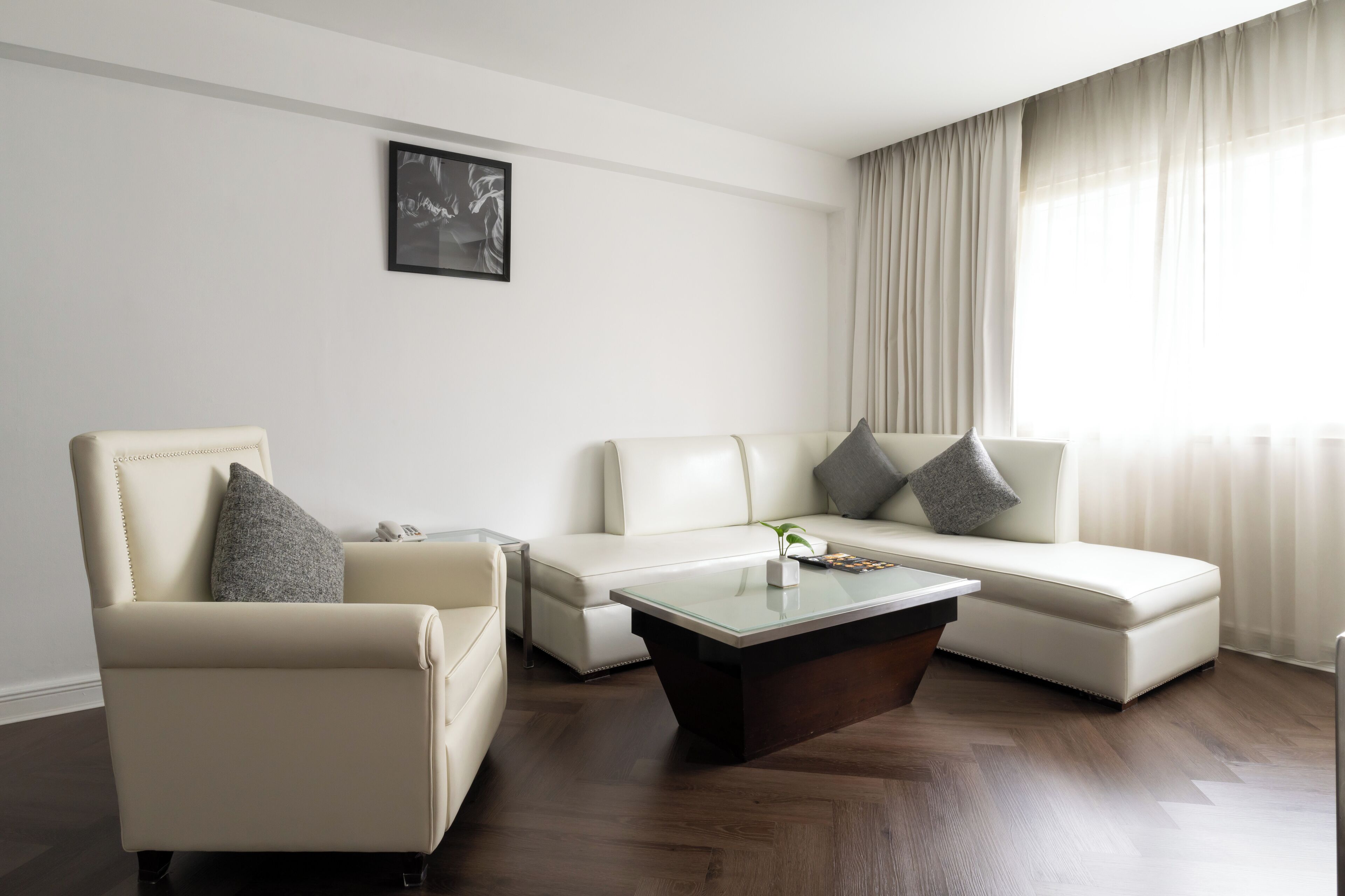 Una sala de estar moderna con un sofá blanco, un sillón a juego y una mesa de centro de vidrio.