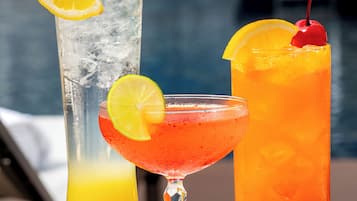 Trois cocktails sont posés sur une table, avec une piscine en arrière-plan.