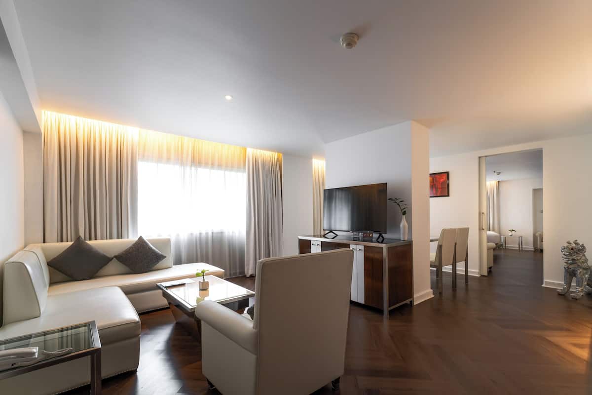A modern living room with a sofa, armchair, and coffee table. There is a TV and a small cabinet in the background.