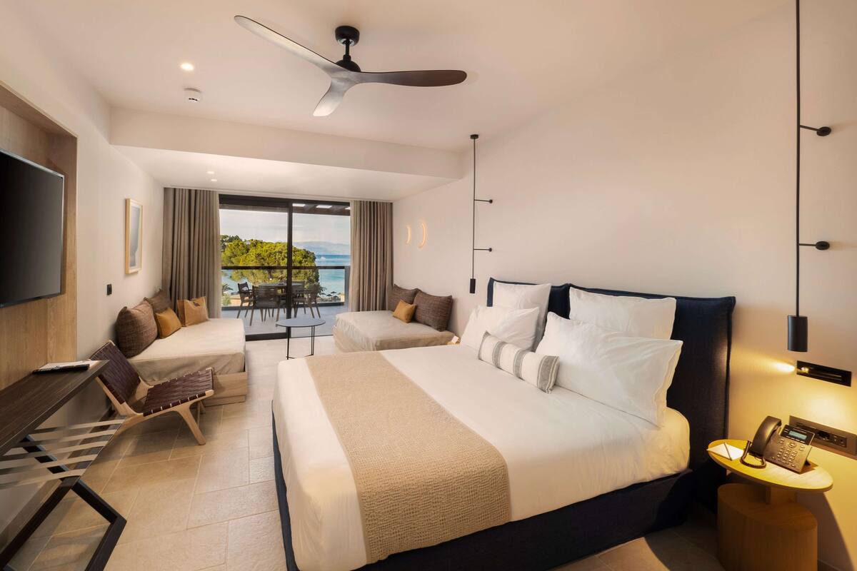 Una habitación de hotel moderna con una cama grande, un escritorio, una silla y un balcón con vista al mar.