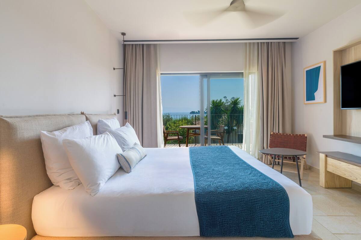 Una habitación de hotel con una cama grande, un escritorio, una silla y un balcón con vistas.
