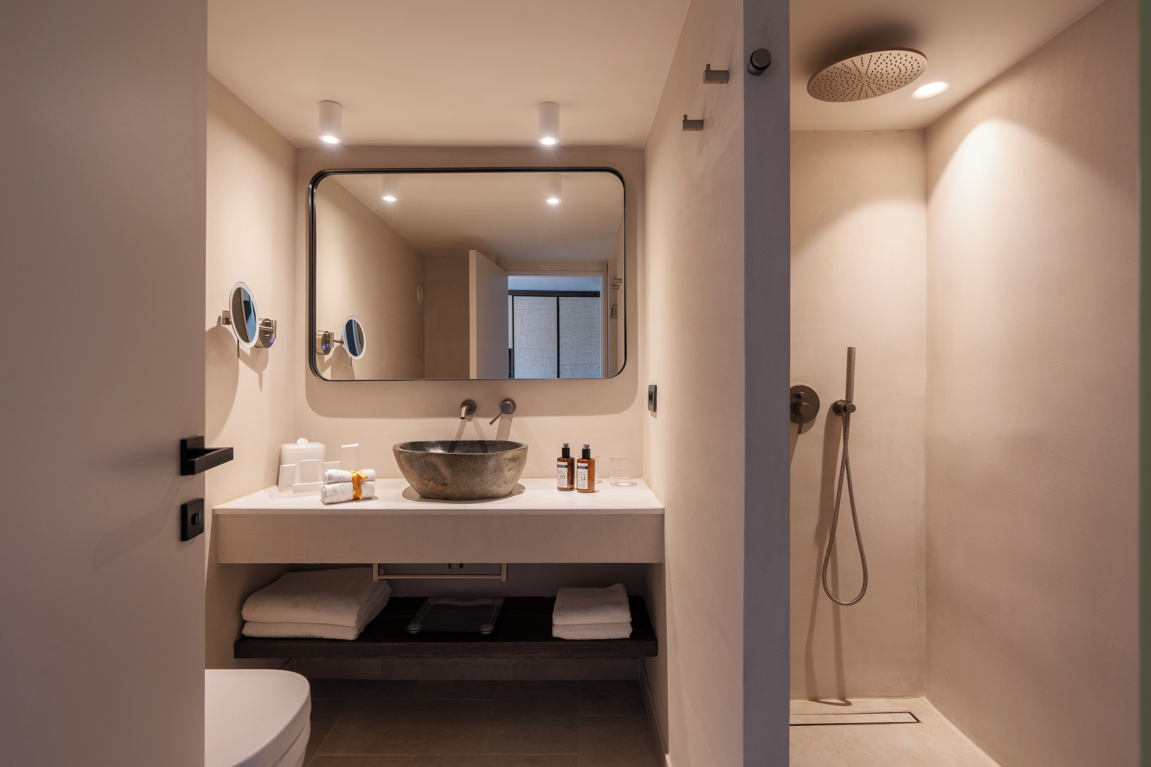 Un baño moderno con un espejo grande, un lavamanos y una ducha.