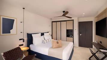 Una moderna camera d'albergo con un letto, una scrivania, una sedia, una ventola a soffitto e una televisione.