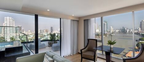 A modern living room with a large window, a sofa, a table, and a chair.