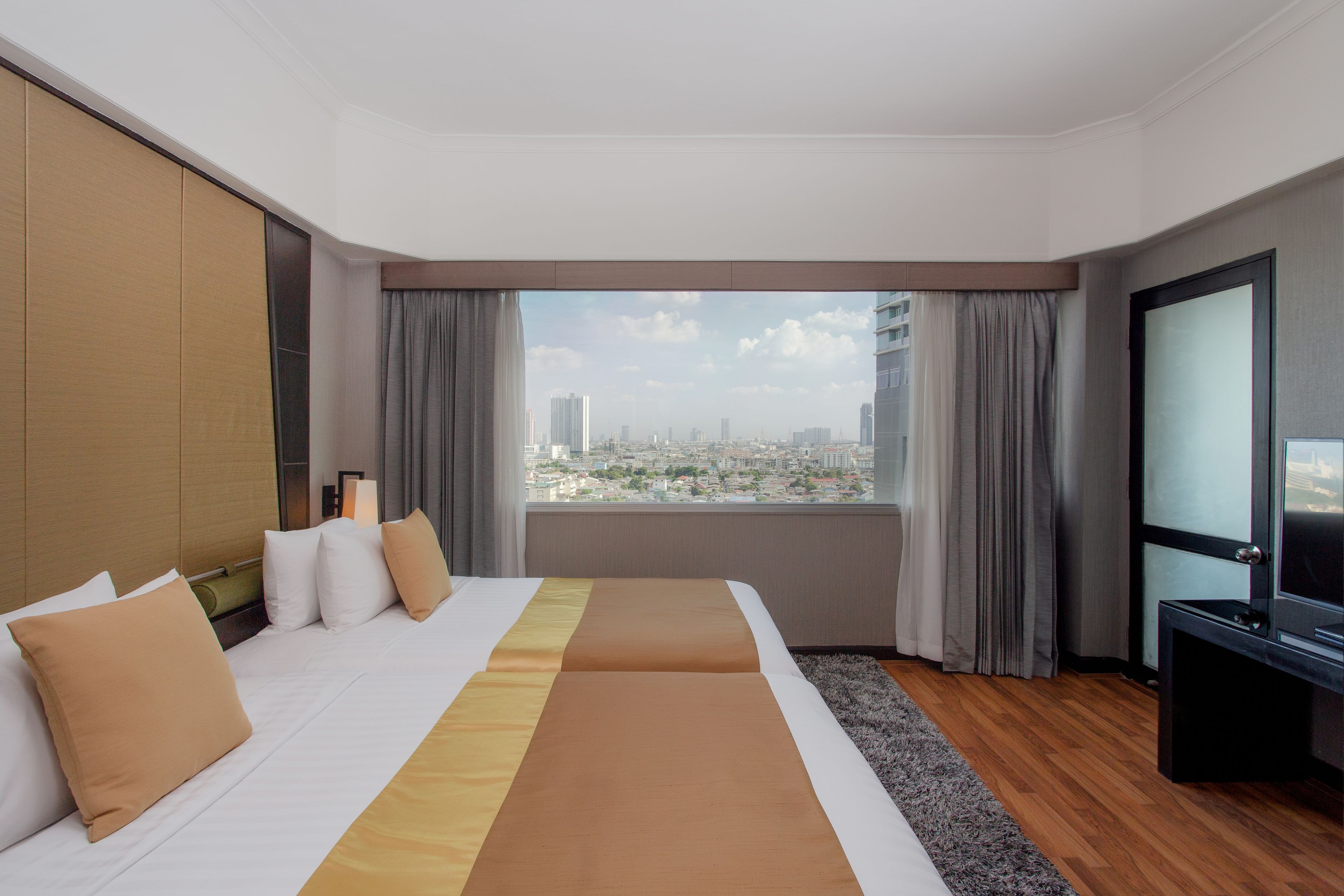 Una habitación de hotel con una cama grande, televisión y vistas a la ciudad por la ventana.