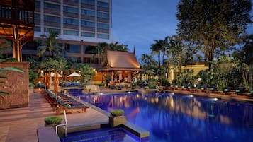 Una piscina al aire libre, sombrillas, sillones reclinables de piscina