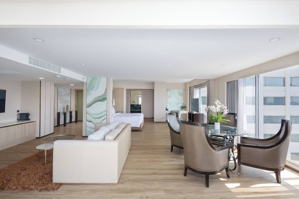 A modern hotel room with a bed, seating area, and a dining table.