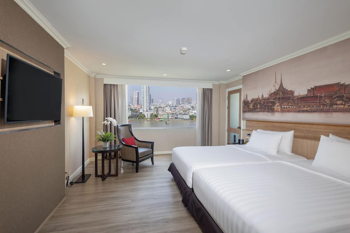 A hotel room with a large bed, a desk with a chair, a flat-screen TV, a painting of a cityscape, and a view of a city skyline.