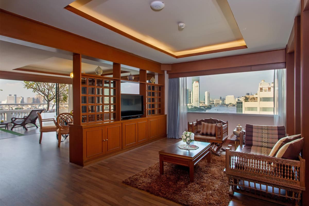 A spacious living room with a large TV, wooden furniture, and a city view.