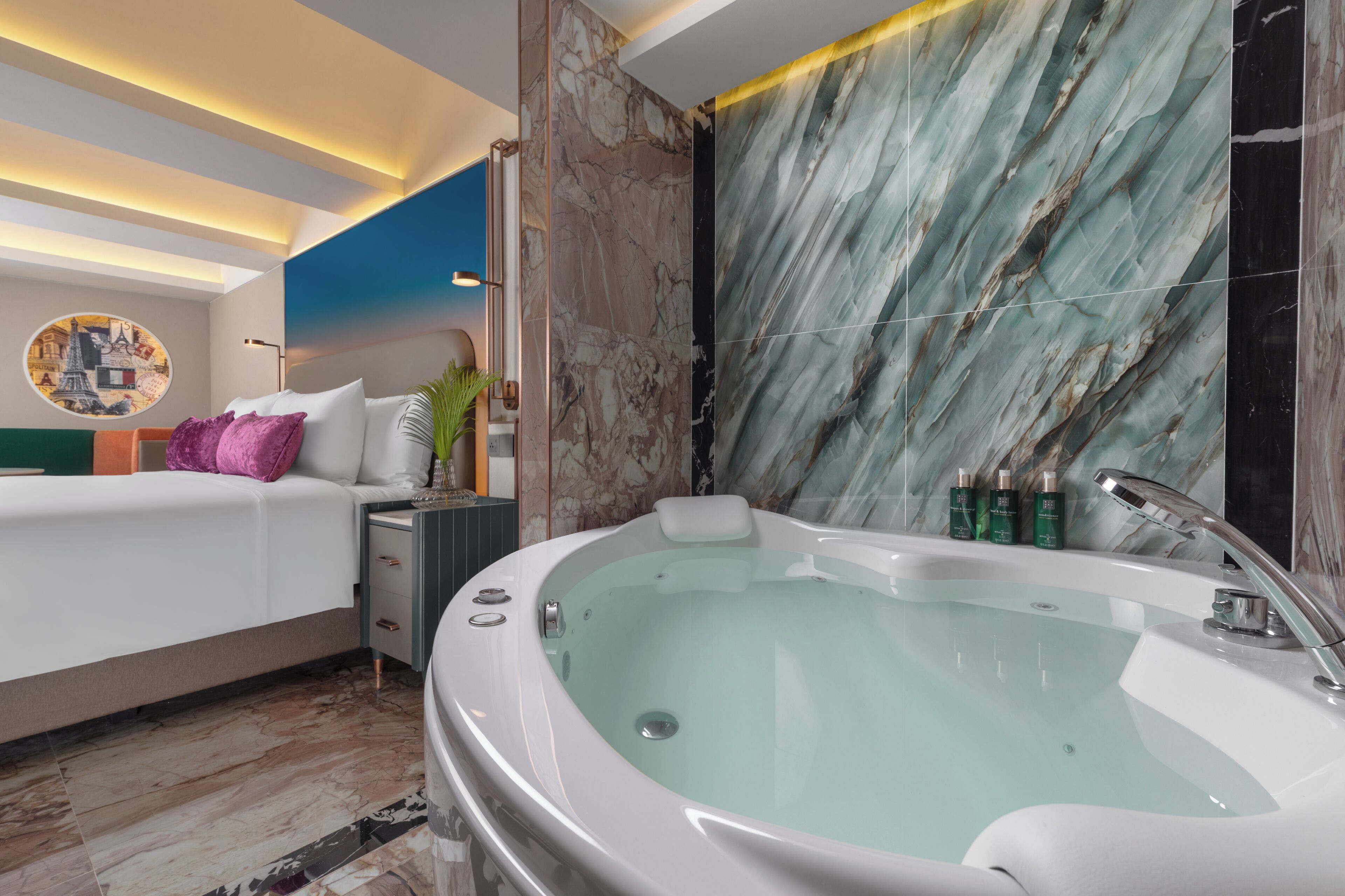 Een moderne hotelkamer met een groot bed, een jacuzzi, marmeren wanden en een stadsgezicht kunstwerk.