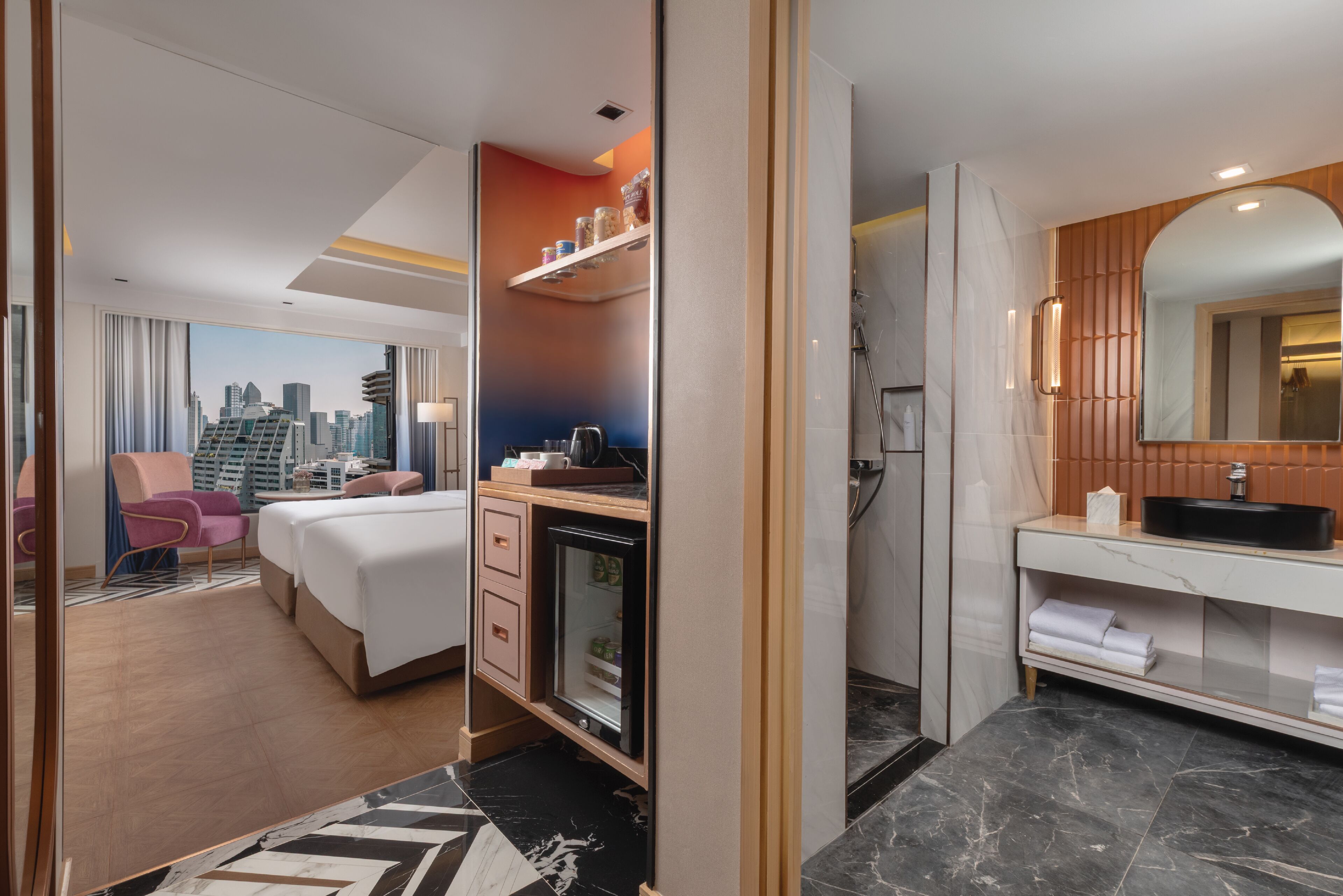 Une chambre d’hôtel avec vue sur la ville, un minibar, une douche et une coiffeuse avec un miroir.