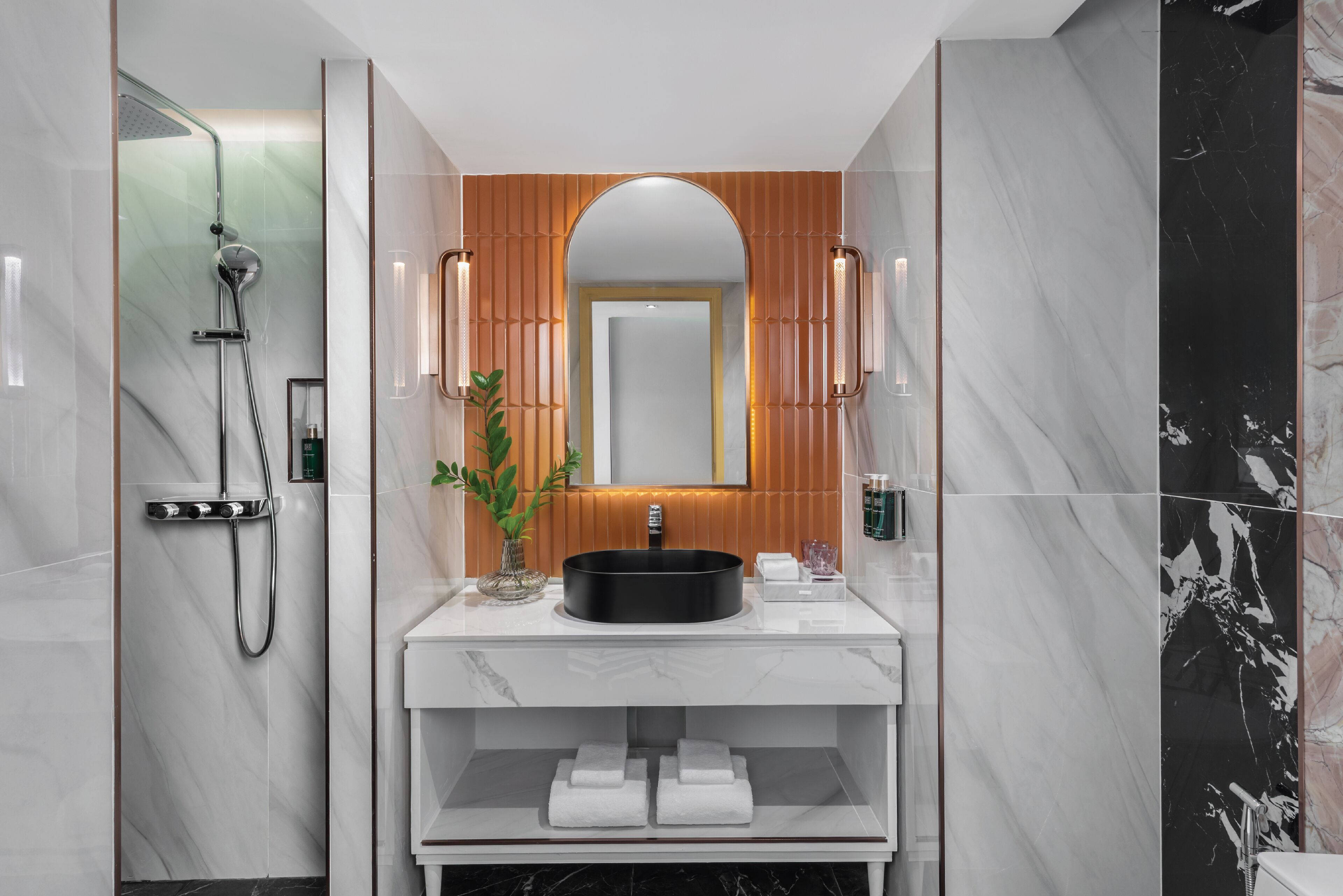 A modern bathroom with a large mirror, a round sink, and a shower.