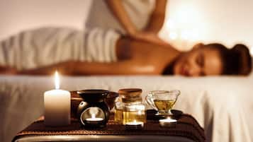 Un ambiente de spa con una vela, aceites esenciales y una pequeña taza sobre una bandeja.