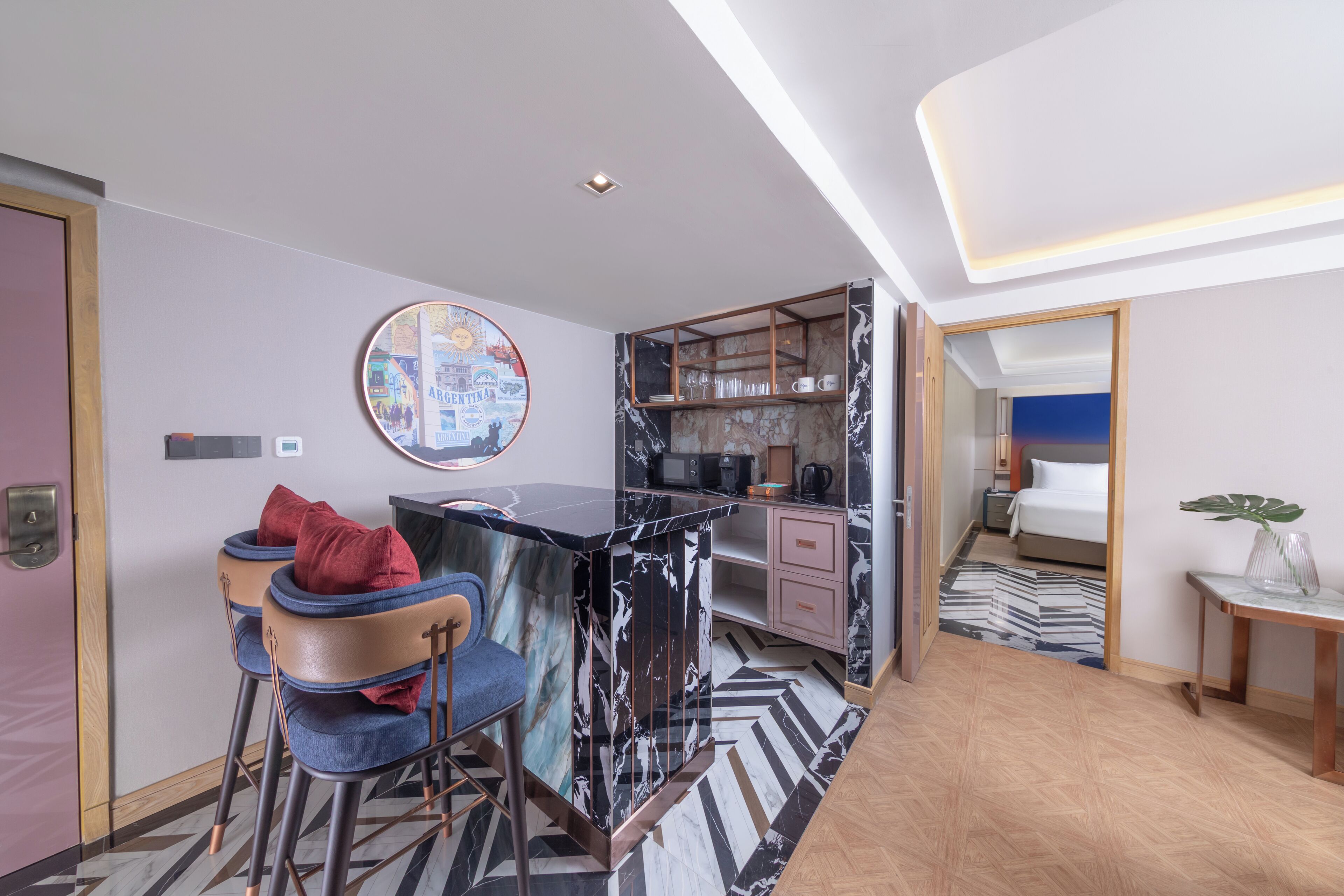 Habitación de hotel moderna con cocina, una mesa de comedor con sillas, una cama y vistas a la ciudad.
