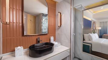 A modern bathroom with a marble vanity, a large mirror, and a glass-enclosed shower.