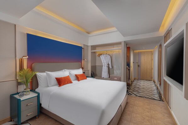 Una habitación de hotel moderna con una cama grande, un vestidor y un televisor.