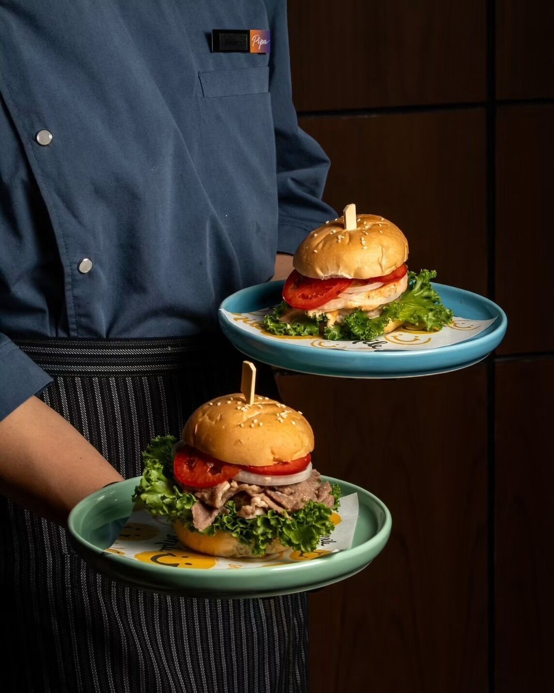 A person holding two plates with burgers.