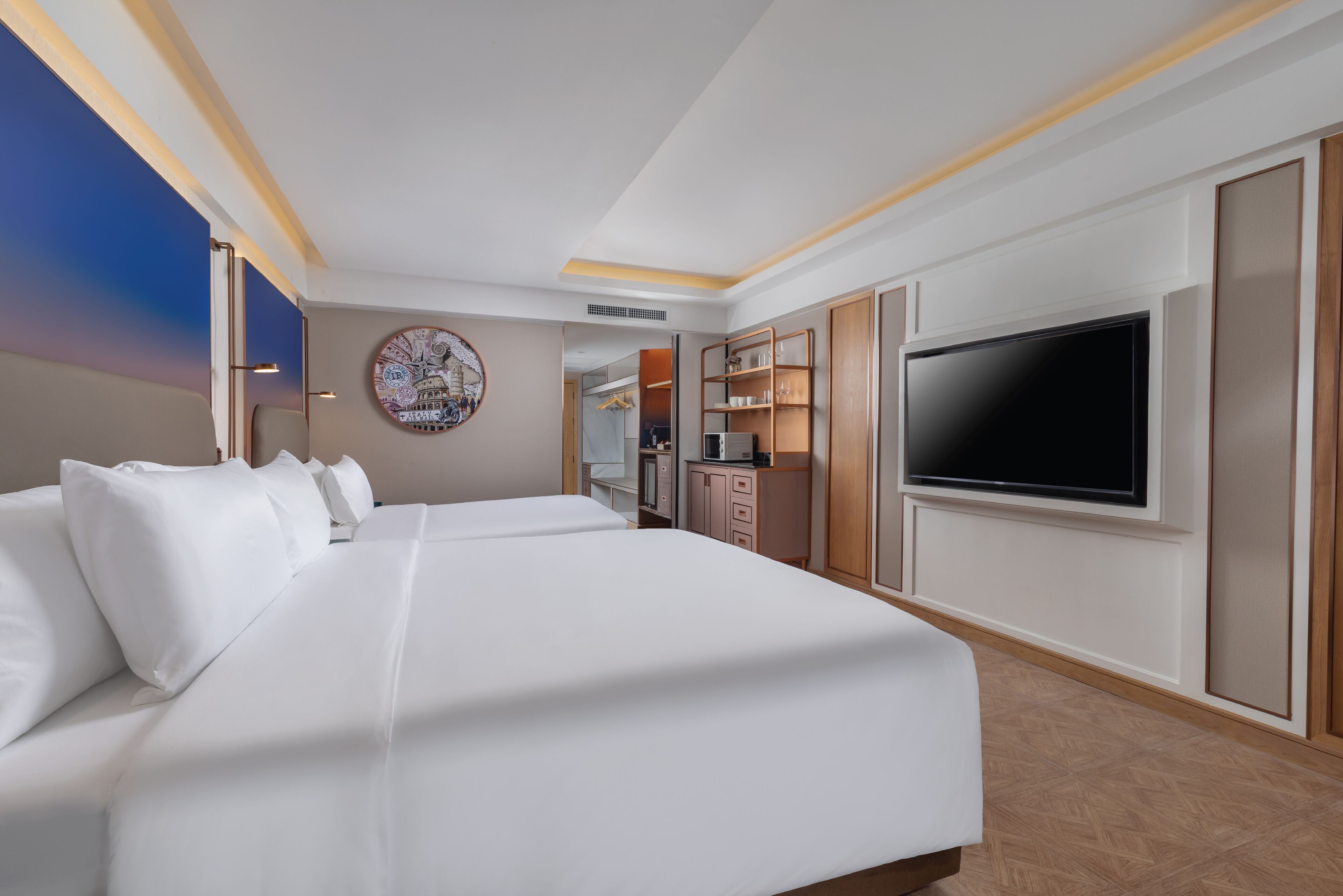 Ein Hotelzimmer mit einem großen Bett, einem Fernseher, einer Küchenzeile und einem durch eine offene Tür einsehbaren Badezimmer.