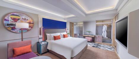 Una habitación de hotel moderna con una cama grande, un televisor, un escritorio y un vestidor.