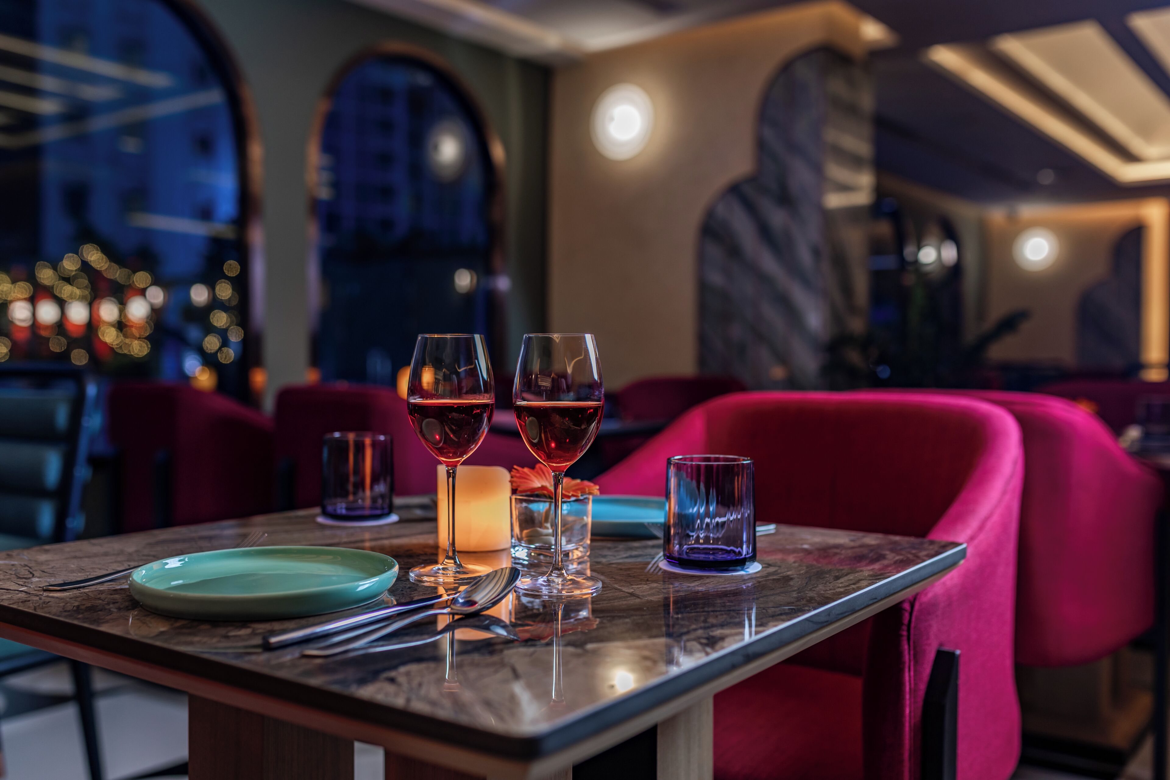 A dining table with three wine glasses, a candle, and a plate.