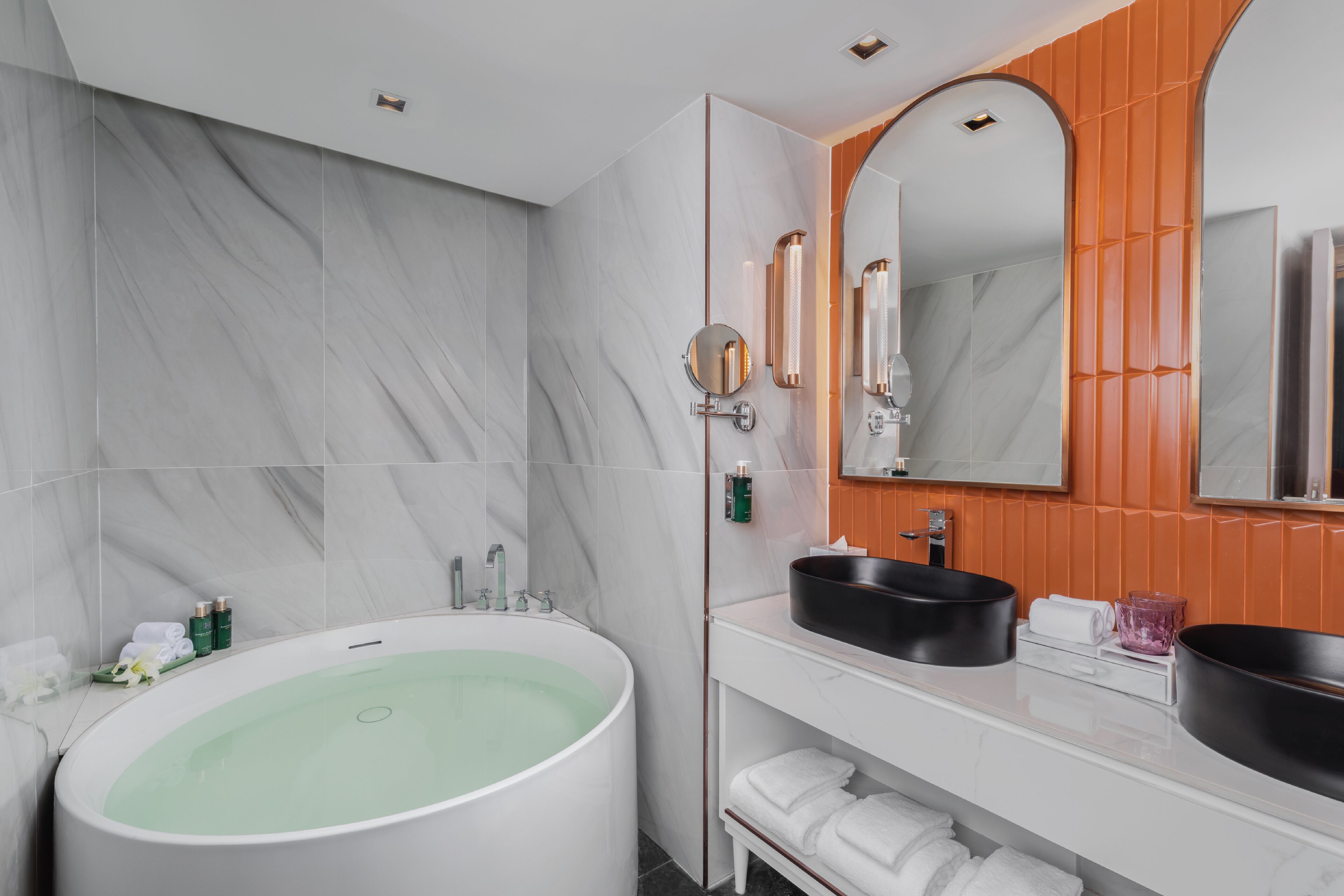 A modern bathroom with a large freestanding bathtub, a vanity with two sinks, and a mirror above the sink.