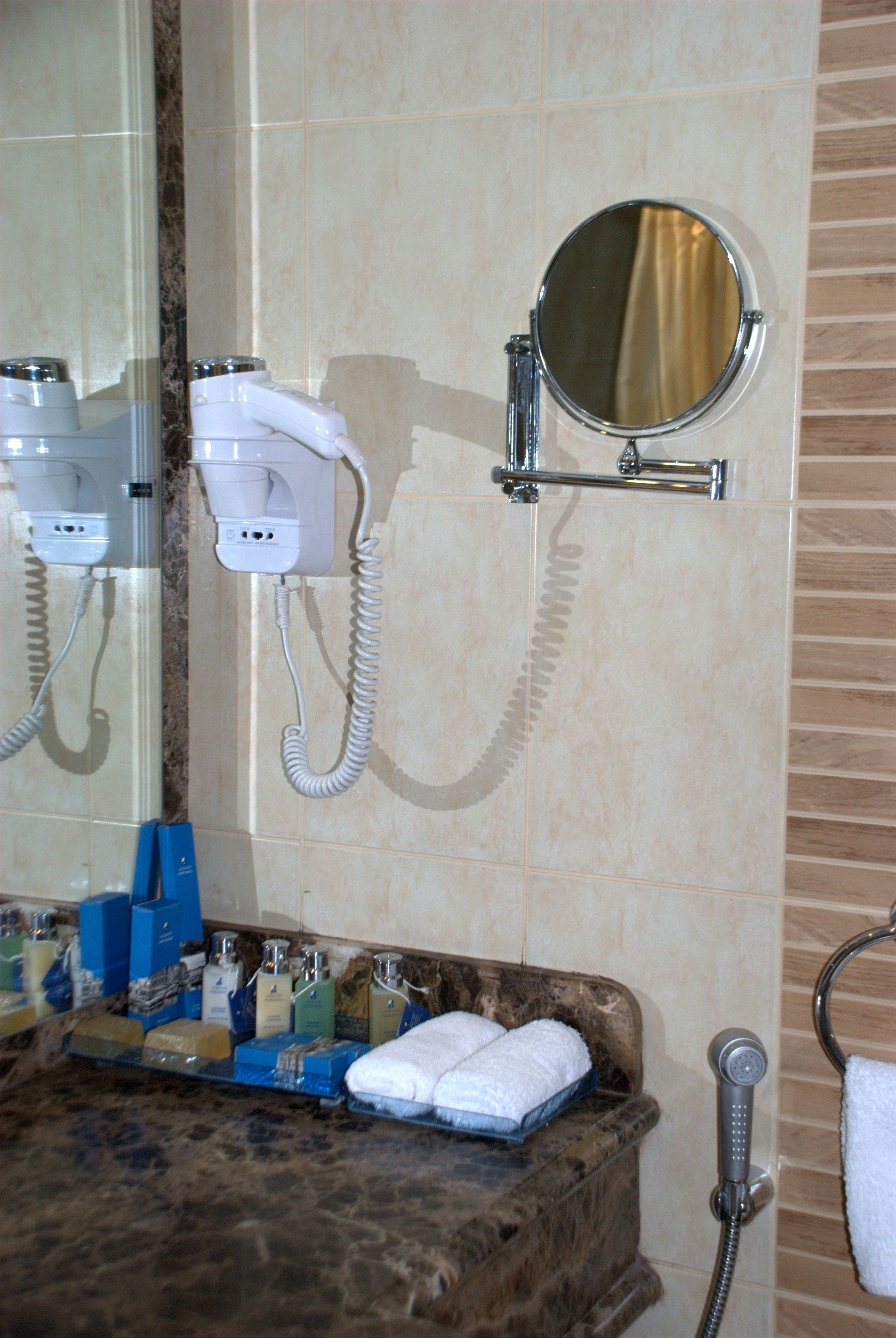 A bathroom with a hairdryer, a mirror, and a towel rack.