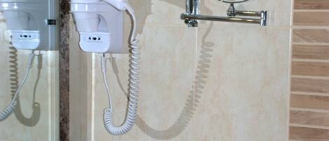 A bathroom with a hairdryer, a mirror, and a towel rack.