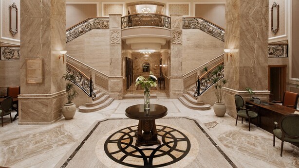 A grand lobby with marble floors, a central round table, and a staircase with ornate railings. - Hilton Cairo Zamalek Residences (Cairo)