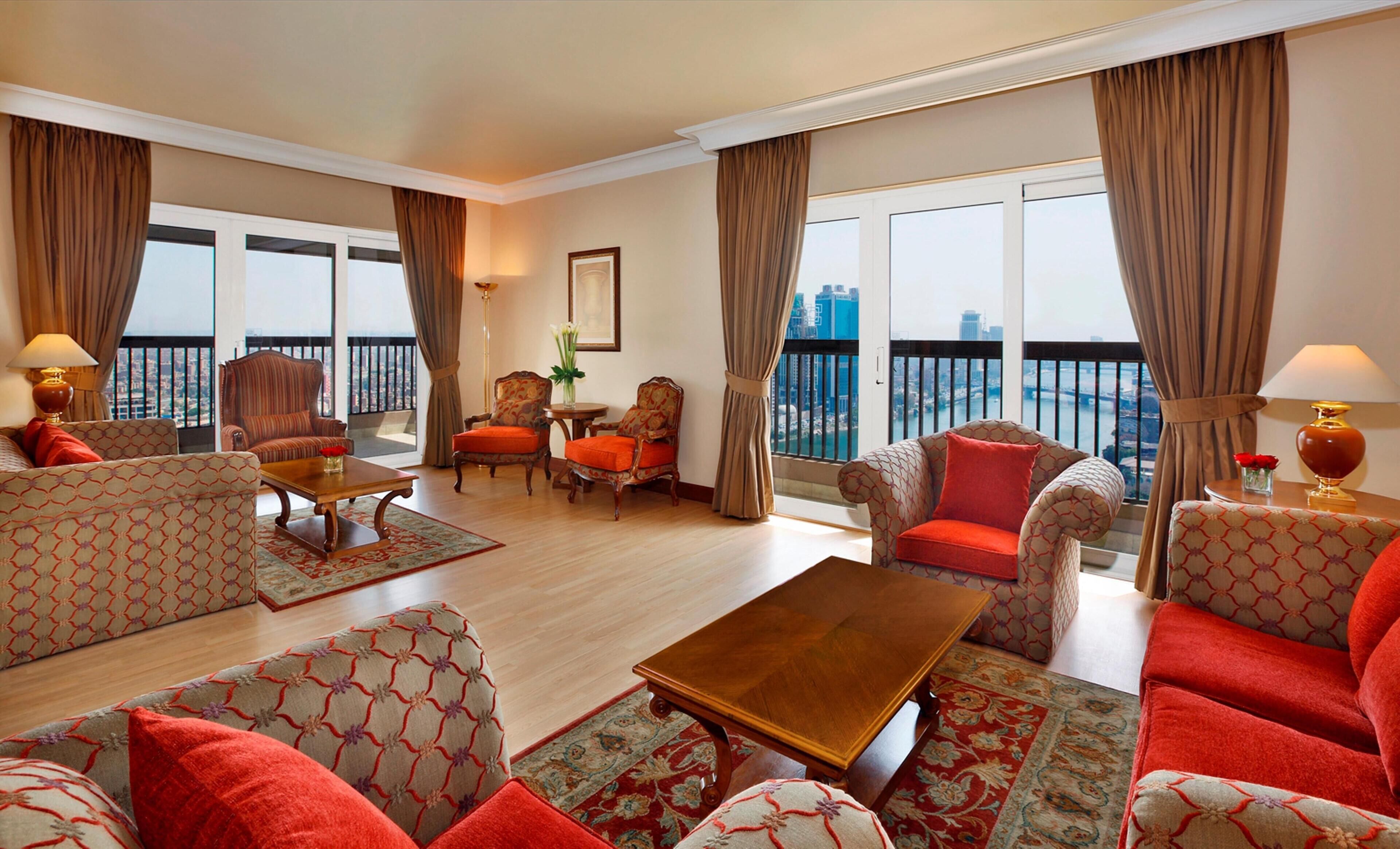 A spacious living room with a balcony, patterned furniture, and a view of the city.