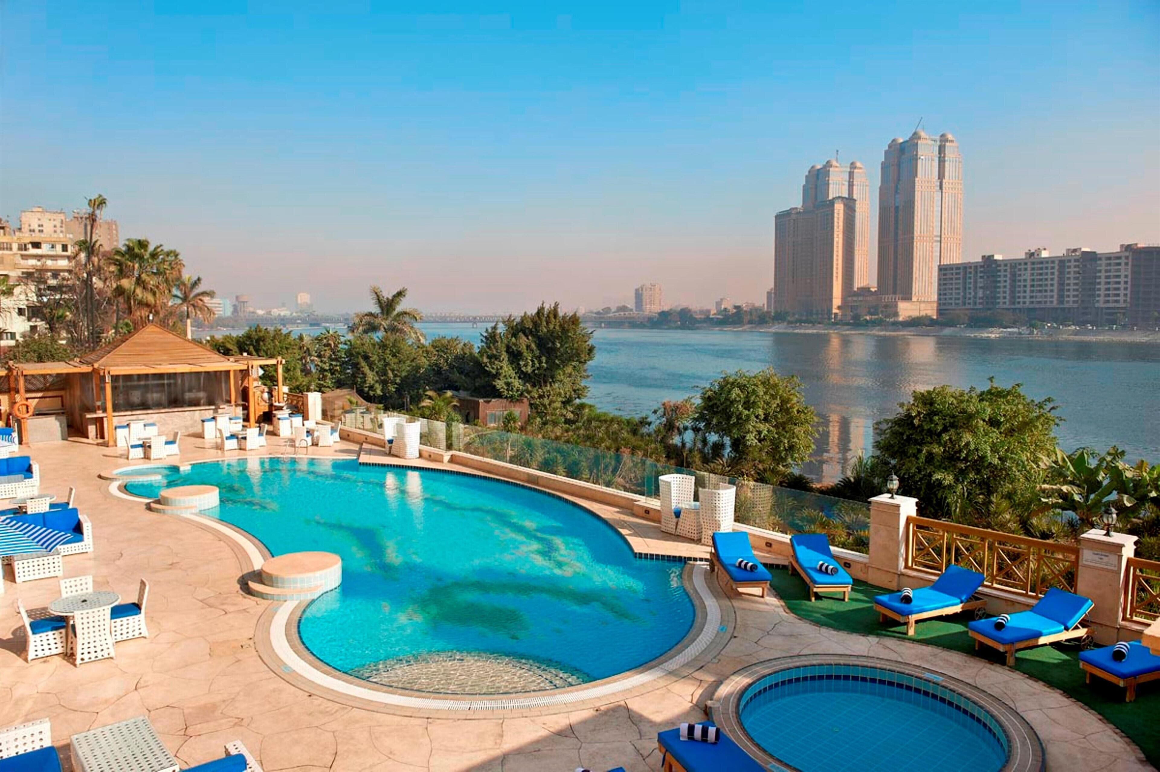 Una piscina al aire libre, sombrillas, sillones reclinables de piscina