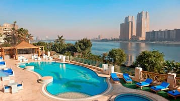 Una piscina al aire libre, sombrillas, sillones reclinables de piscina