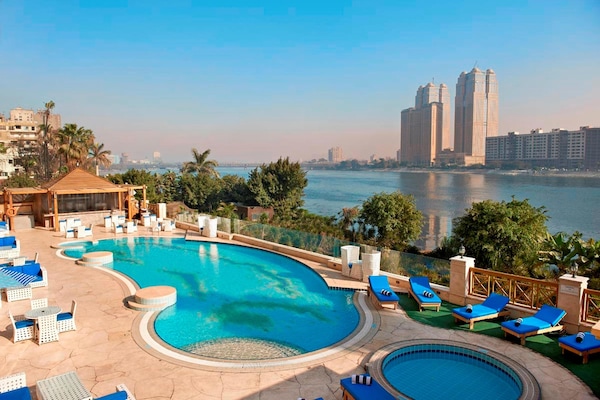 Una piscina al aire libre, sombrillas, tumbonas