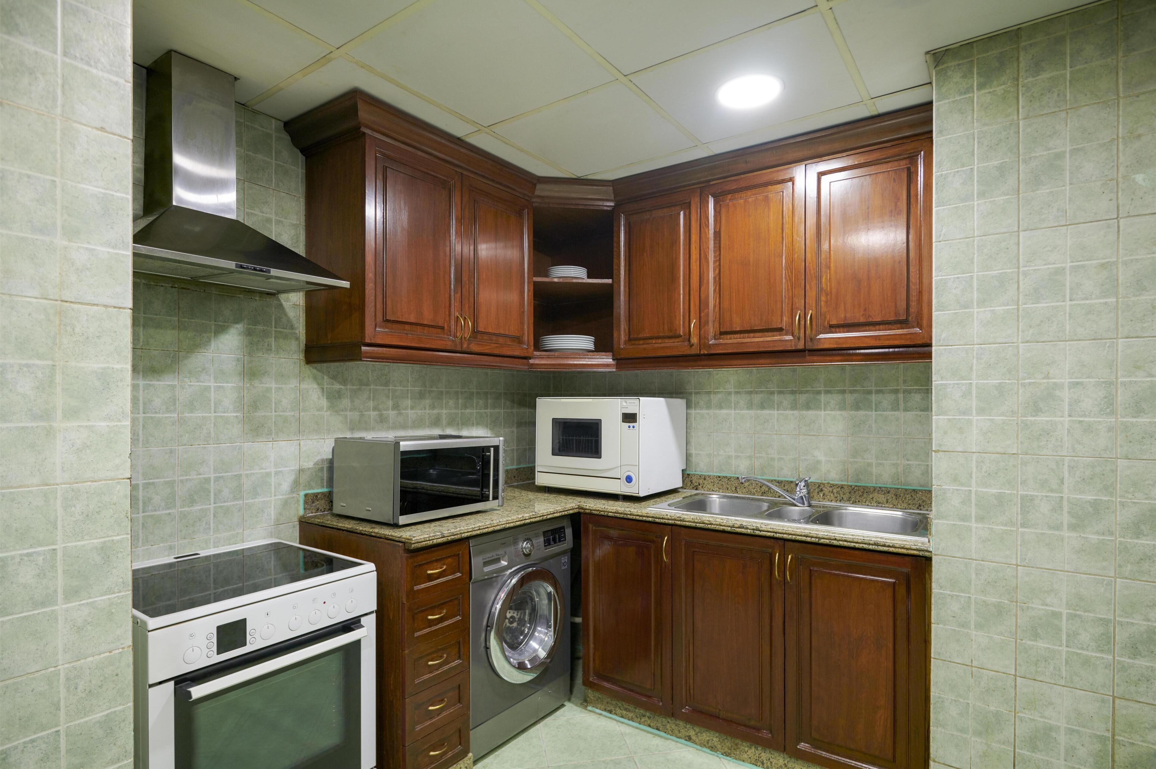 A compact kitchen with a microwave, oven, and washing machine.