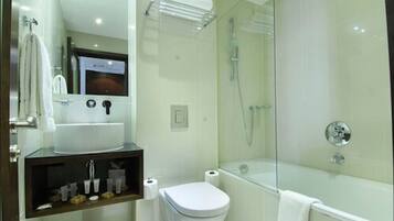 Un baño moderno con ducha de vidrio, un lavabo blanco y un inodoro.
